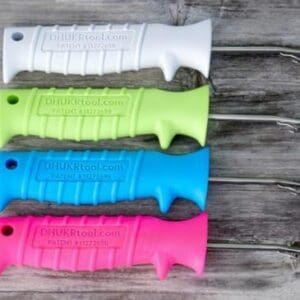 Four colorful knives with serrated blades arranged vertically on a wooden surface.